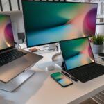 A contemporary workspace featuring a laptop, tablet, smartphone, and monitor displaying abstract backgrounds.